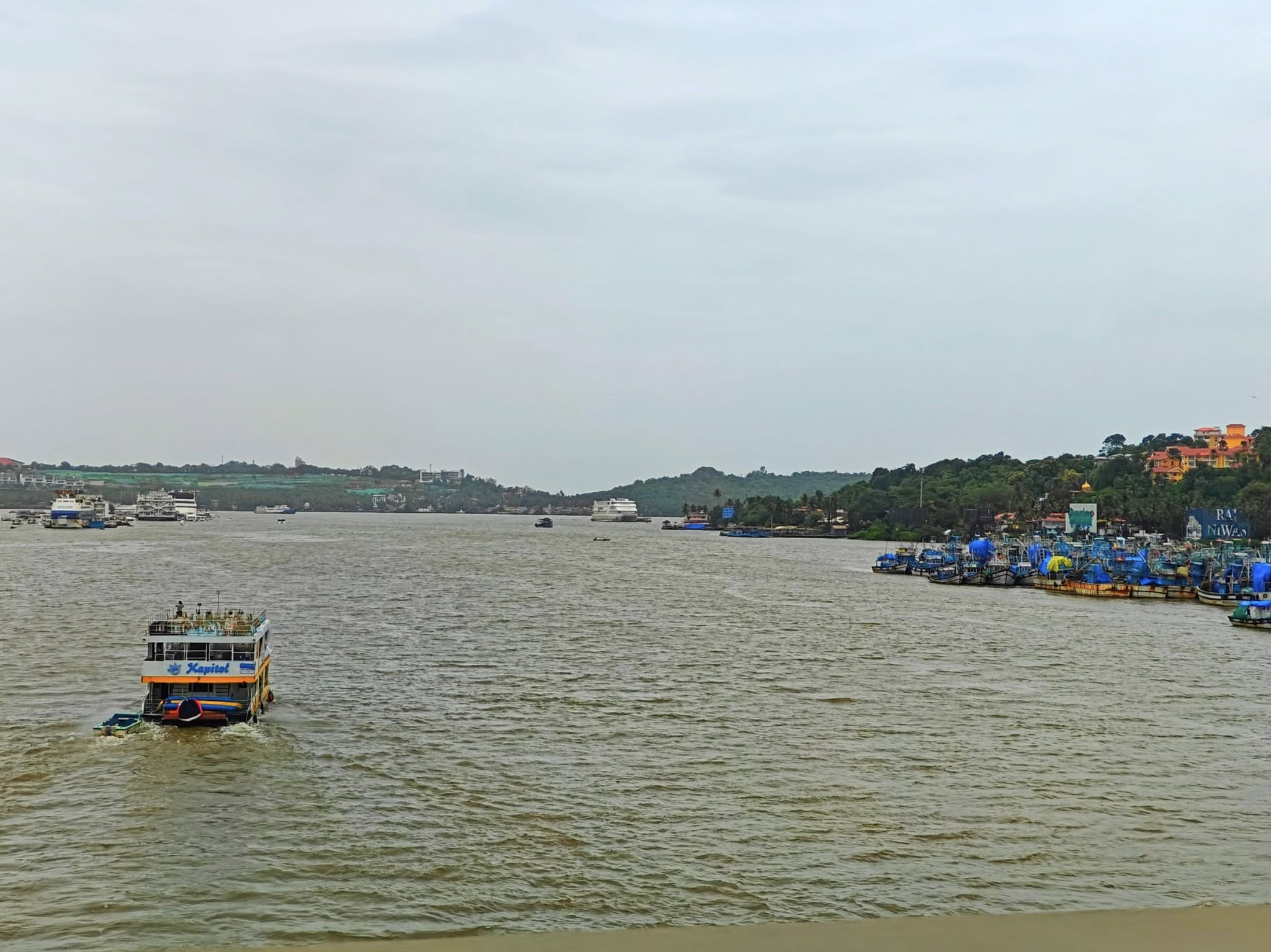 Mandovi River cruise in Goa, sailing past scenic waterfront views under a vibrant sunset sky.