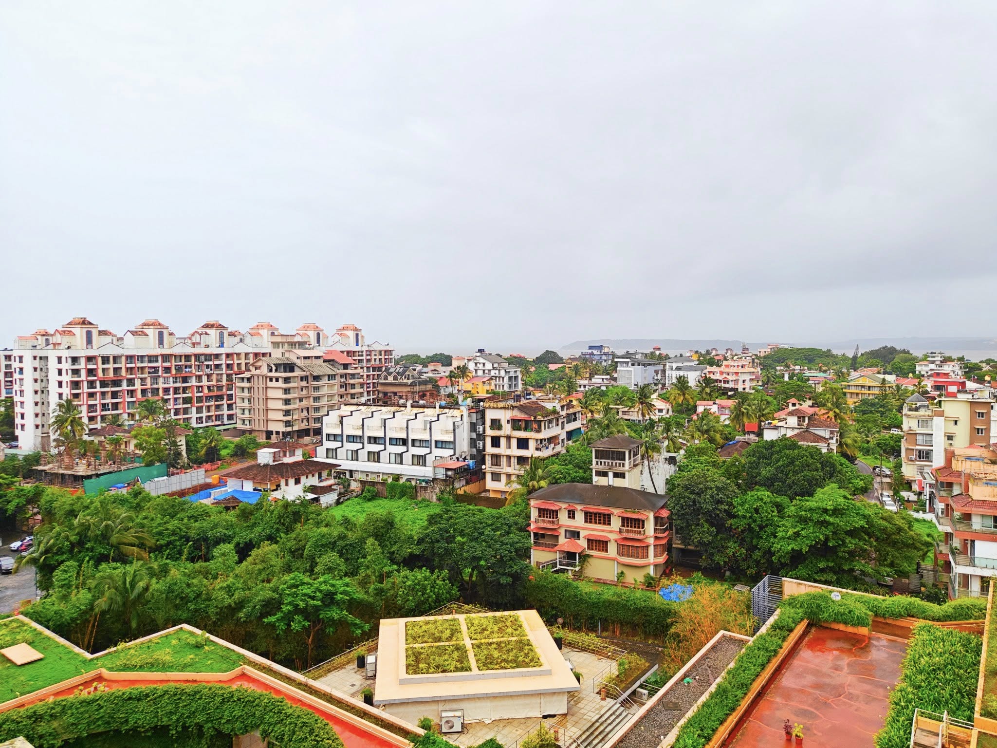 Colorful waterfront cityscape of Panaji in North Goa, with Portuguese-style buildings lining the Mandovi River under a clear blue sky.
