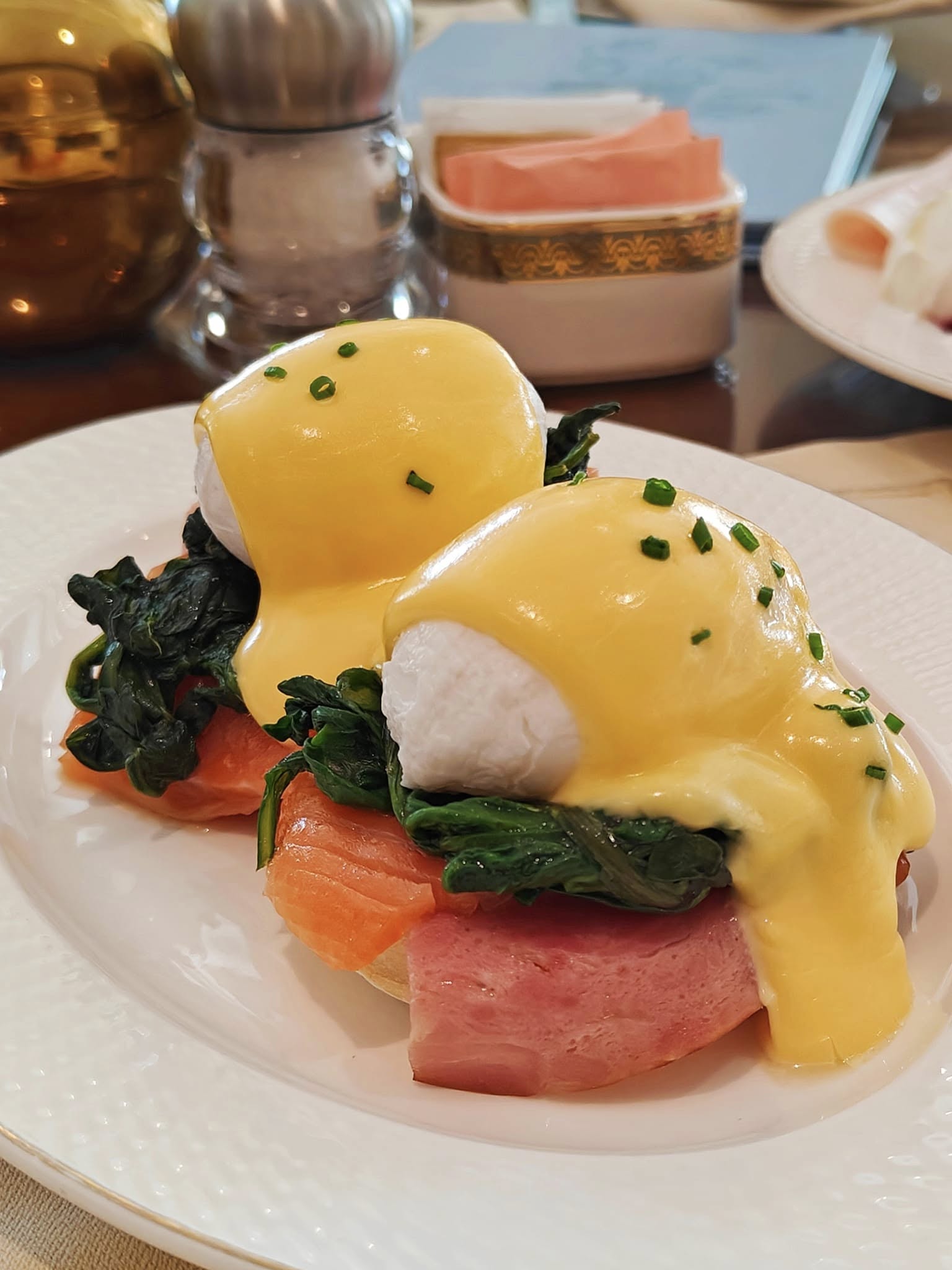 Eggs Benedict with poached eggs, hollandaise sauce, and garnish served for breakfast at Raffles The Palm, Dubai.