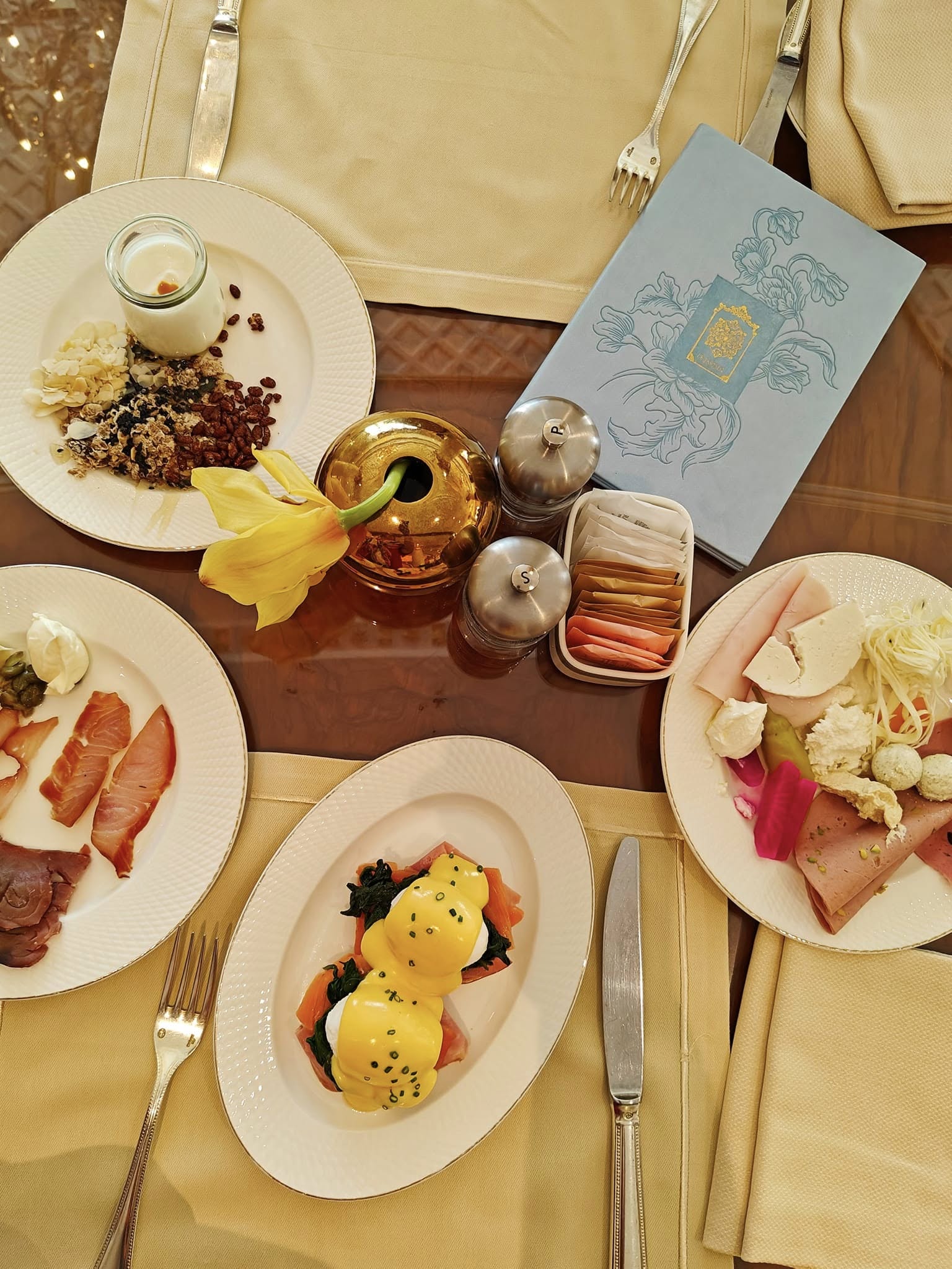 Elegant breakfast spread at Raffles The Palm Dubai featuring an assortment of pastries, fresh fruit, gourmet dishes, and fine tableware set against a refined dining backdrop.