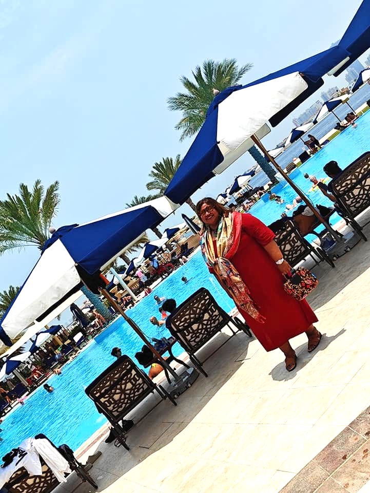 Private beach at Raffles The Palm Dubai with soft white sand, turquoise waters of the Arabian Gulf, neatly arranged sun loungers, and palm trees lining the shore.