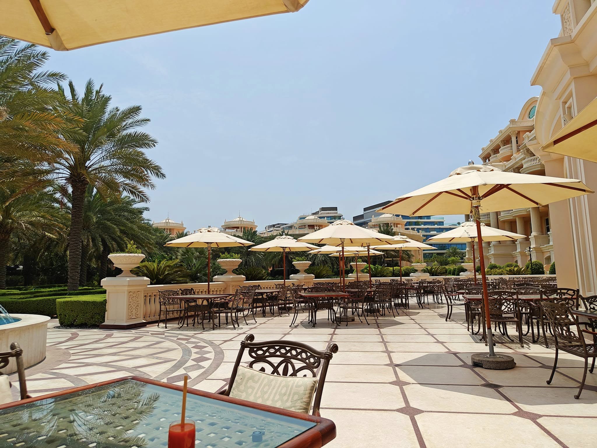 Poolside patio with lounge seating beside a turquoise swimming pool at Raffles The Palm Dubai.