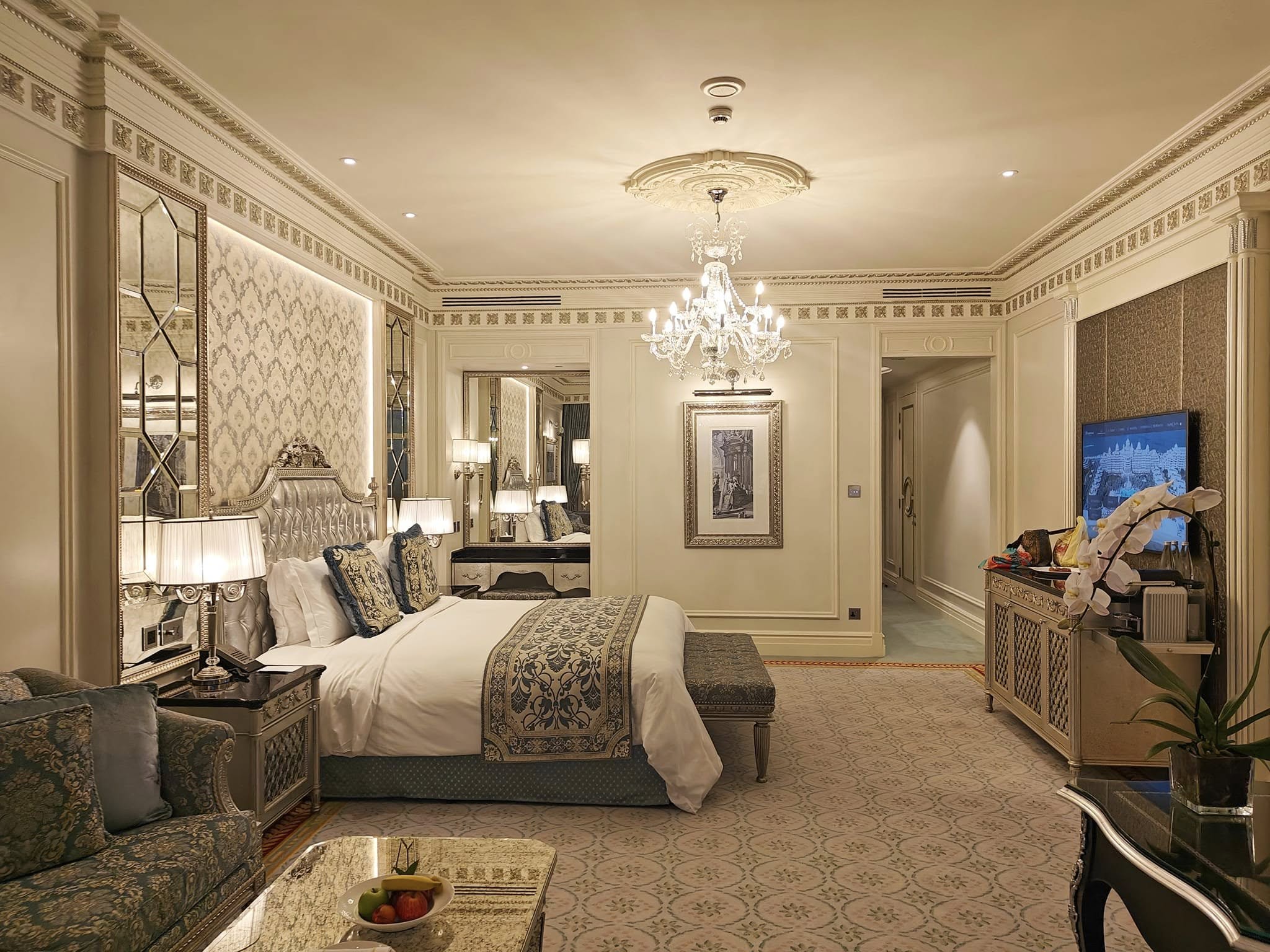 Spacious Premier Ocean View Room at featuring a plush king-size bed, elegant gold-accented dΓ©cor, crystal chandelier, marble bathroom, and large windows overlooking the Arabian Gulf.