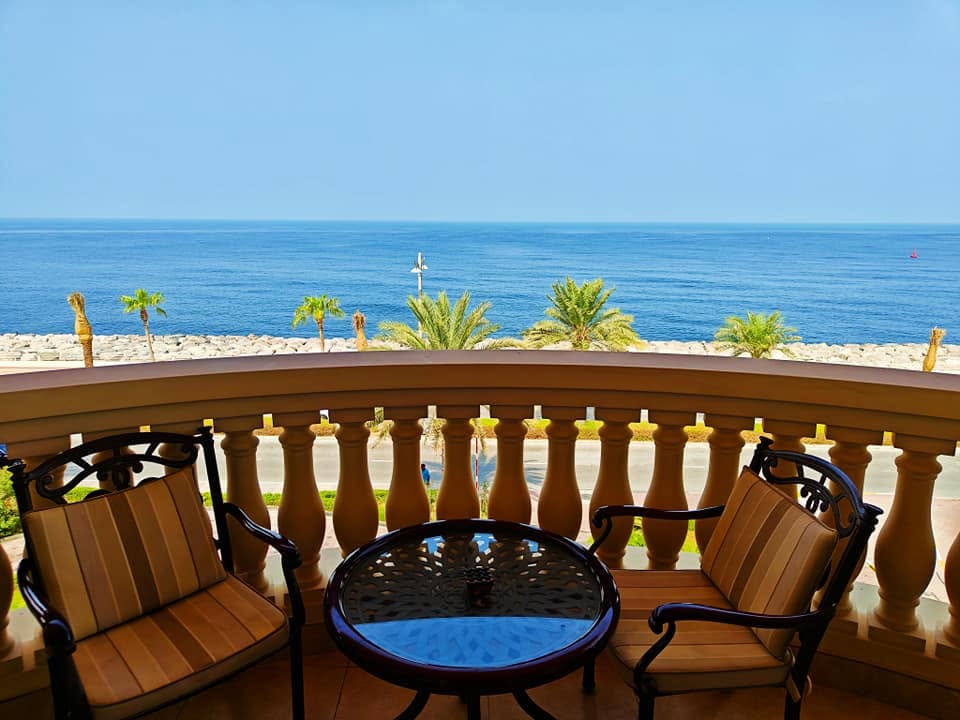 Private balcony of the Premier Ocean View Room at Raffles The Palm Dubai with outdoor seating and panoramic views of the Arabian Gulf and Palm Jumeirah coastline.