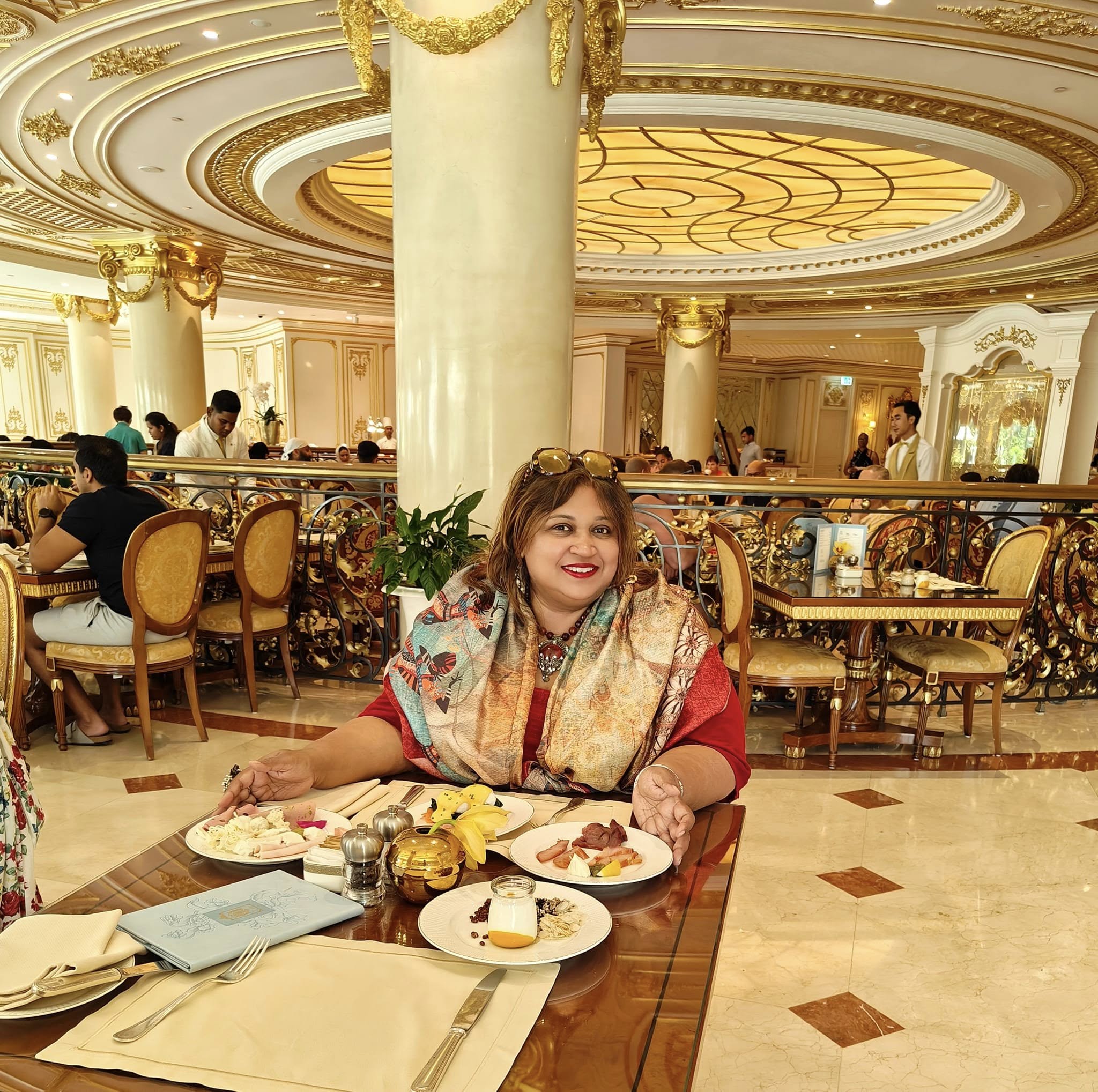 Elegant breakfast table at Raffles The Palm Dubai with pastries, fresh fruit, and coffee overlooking Palm Jumeirah.