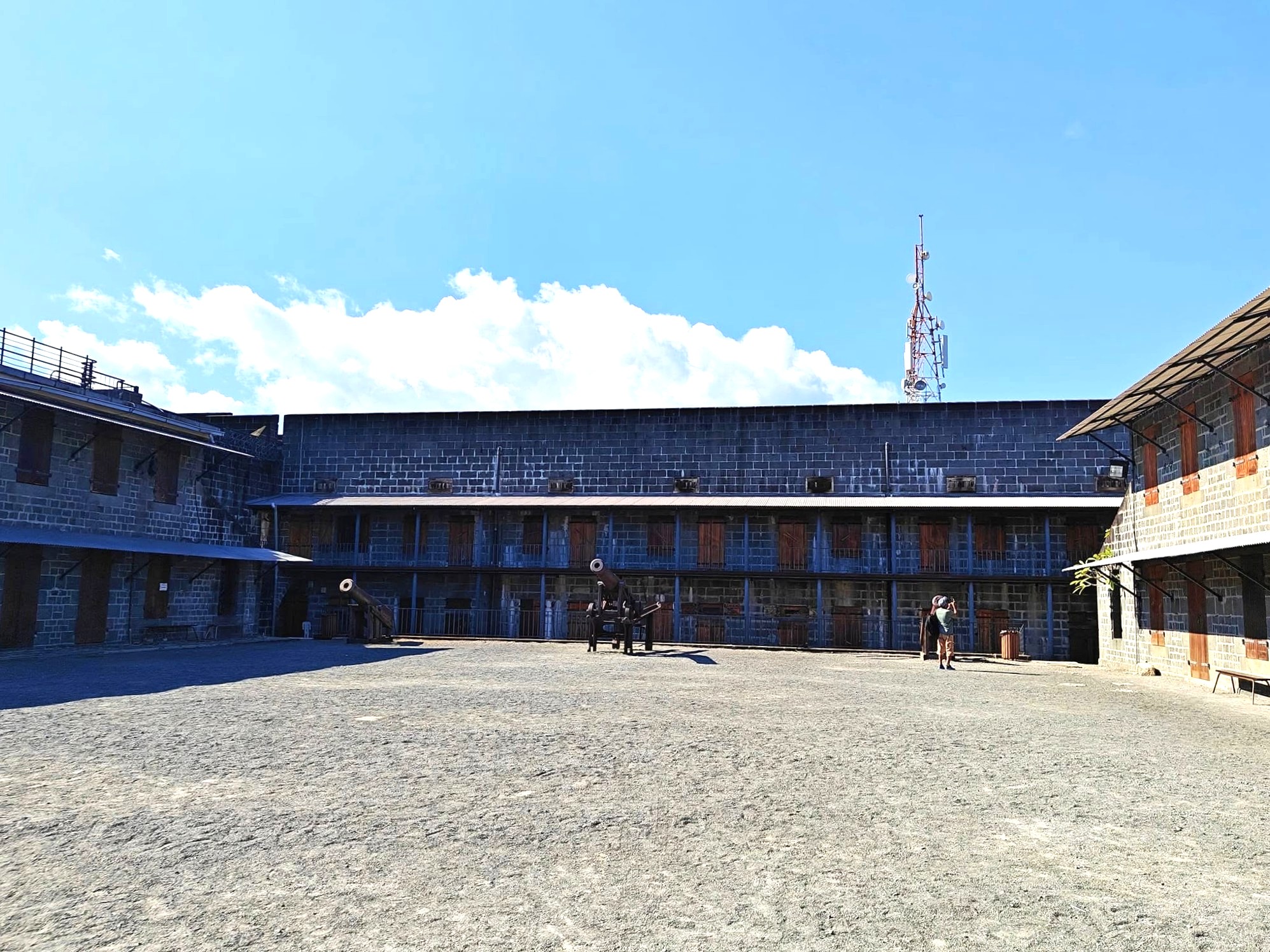 The sunlit central courtyard of La Citadelle Fort in Port Louis, Mauritius, framed by colonial-era stone archways and well-kept grounds