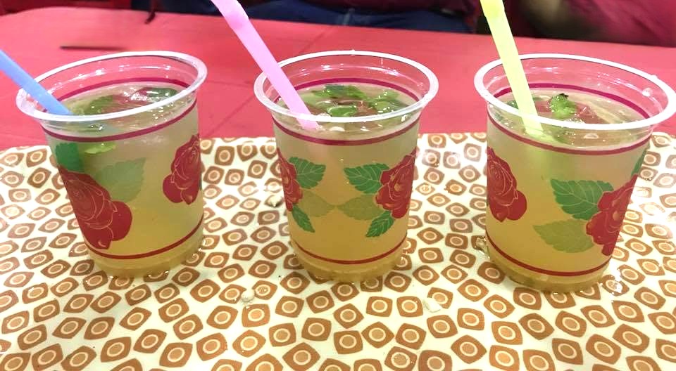 Glass of nimboo masala cooler (Indian spiced lemonade) garnished with lemon and mint.